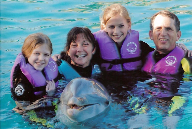 Dick Dropkins family. From left to right is: Jacqui (daughter), Joni (wife), Danielle (daughter), and Dick. The dolphin in the front is not part of the family.